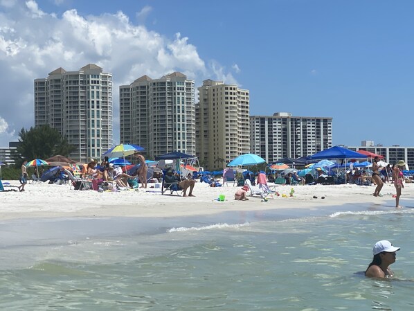 Een strand met parasols en mensen.