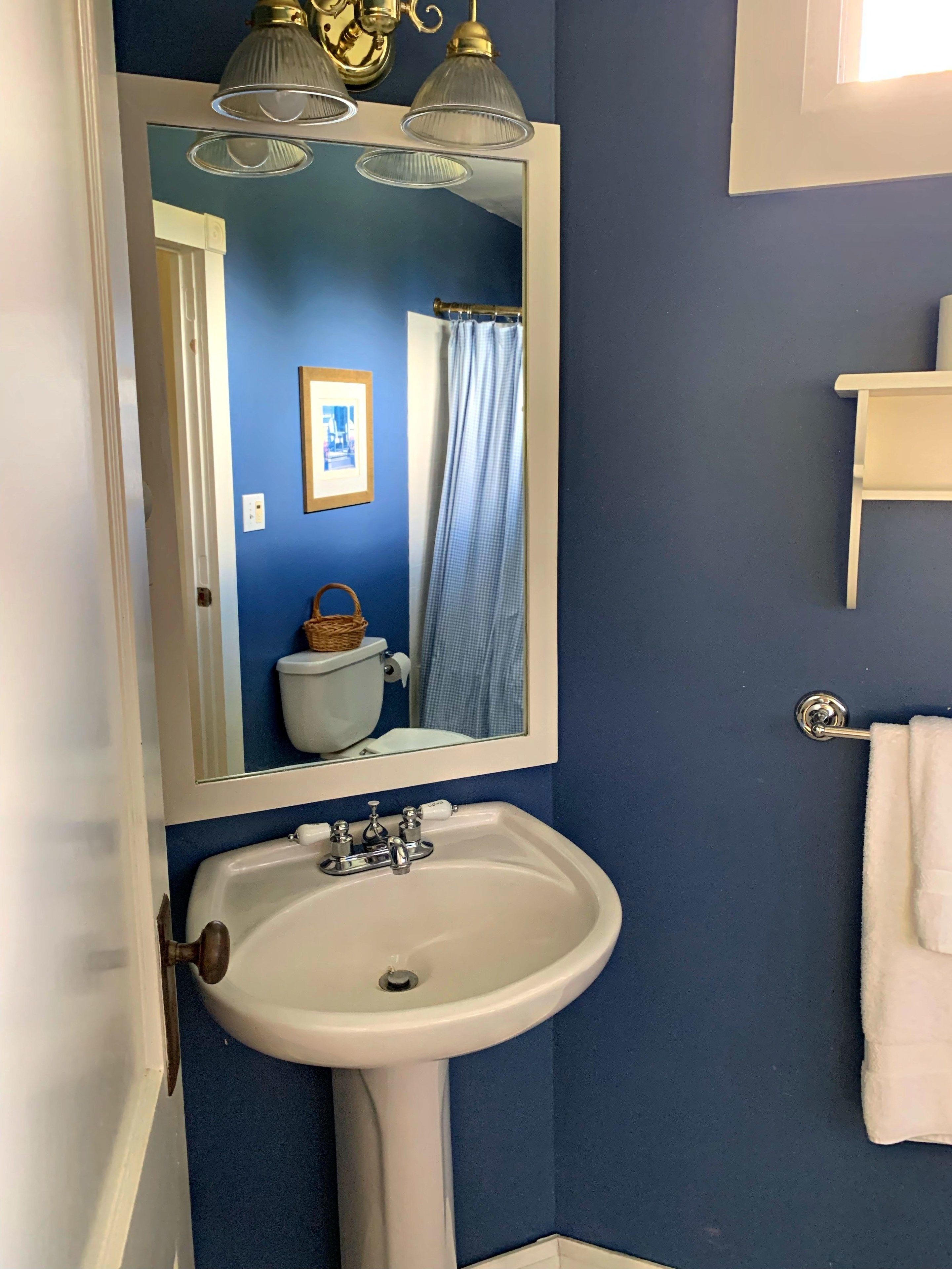 A bathroom with a white sink, a mirror above it, and a blue wall.