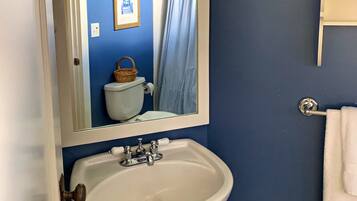 A bathroom with a white sink, a mirror above it, and a blue wall.