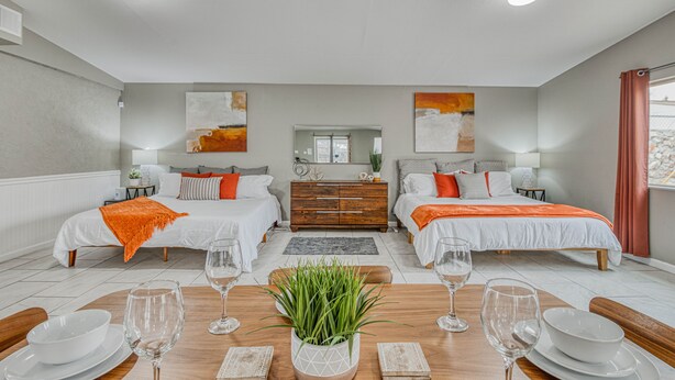 A modern hotel room with two beds, a dining table with white plates and glasses, and a central plant. - 🌞6 KING beds, 14 GUESTS, 5 BEDROOMS, 2 BATHROOMS, REFRIGERATION, NEAR AIRPORT (El Paso)