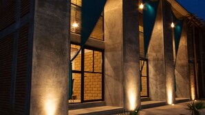 A modern building with large windows and a sloped roof, illuminated by exterior lights. - Hotel El Refugio Campestre (Oaxaca)