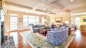 A spacious living room with a large sectional sofa, a fireplace, and a view of the outside through large windows.