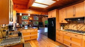 A spacious kitchen with wooden cabinets, a black refrigerator, and granite countertops.