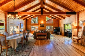 A spacious wooden cabin interior with a dining area, living room, and large windows providing natural light. - Secluded  and PRIVATE Sierra Nevada Foothills vineyard home  (Colfax)