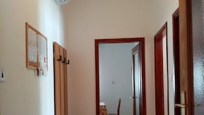 A hallway with a wooden bench, a door with a glass panel, and a chair in the distance.