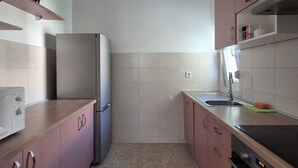 A kitchen with a refrigerator, oven, sink, and cabinets.