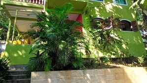 Una casa a due piani con facciata verde, tetto in tegole rosse e un piccolo balcone.