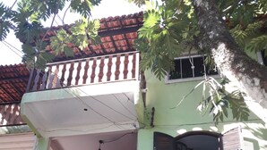 Un edificio a due piani con un balcone, circondato da un lussureggiante verde.