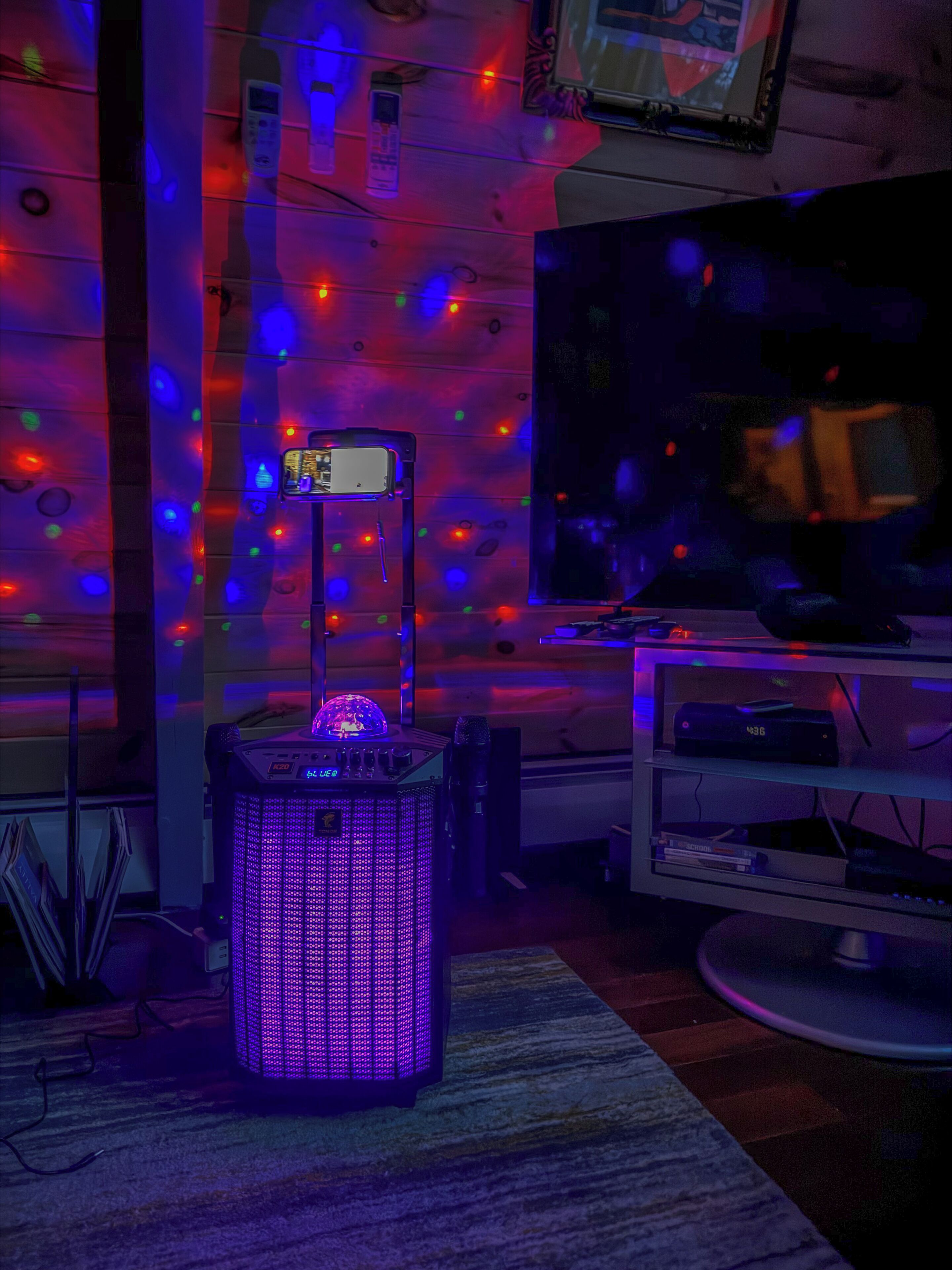 A room with a large flat-screen TV, a DJ mixer, and a decorative LED light.
