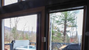 Eine Holzterrasse mit Whirlpool, Grill und überdachter Sitzgruppe.