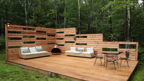 Eine Terrasse aus Holz mit einer Couch, Stühlen und einem Tisch.