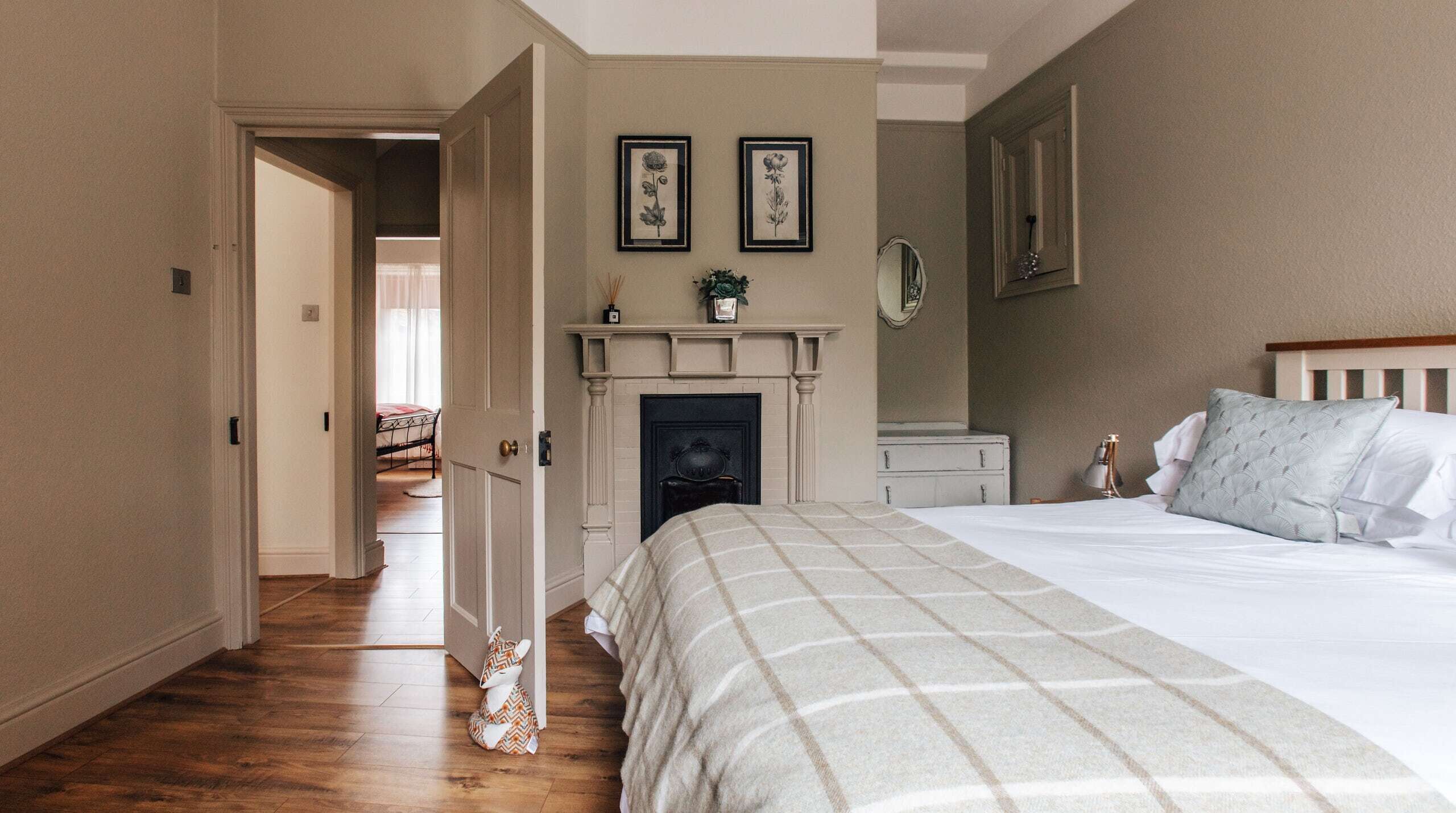 A bedroom with a bed, a fireplace, a door leading to another room, and a hallway.