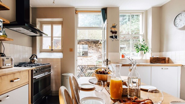 Una cocina con estufa a gas, hervidor de agua y una mesa lista para el desayuno.
