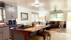 A spacious kitchen with a central island, white chairs, and a dining table. - Maes Cottage In The Clouds (Blue Ridge)