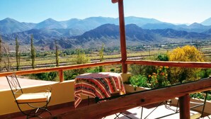 Ein Balkon mit Tisch und Stuhl, mit Blick auf eine Berglandschaft.