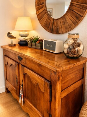 A wooden dresser with a mirror, a lamp, a radio, and decorative items.