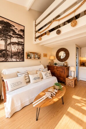 A living room with a sofa, a coffee table, a wooden cabinet, a mirror, and a painting on the wall.