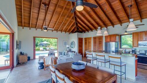 Una cocina amplia con armarios de madera, una isla central y un comedor con una gran mesa de madera.