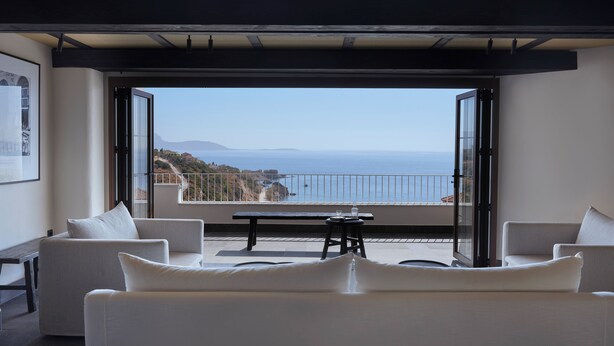 A modern living room with a large balcony overlooking the sea.