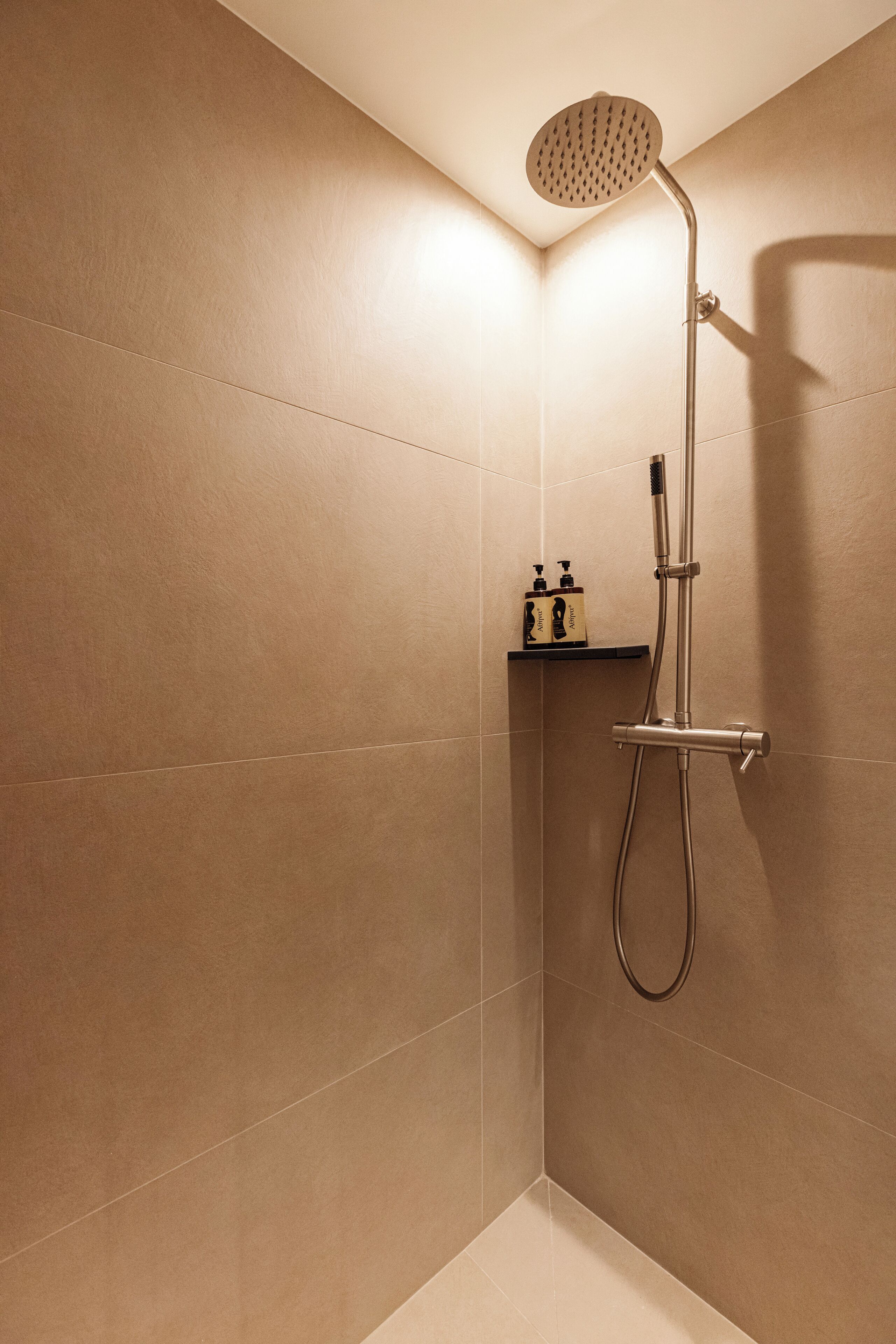 A modern shower with a handheld showerhead and a wall-mounted control.