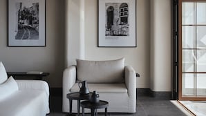 A modern room with a sofa, a small table, and two framed black and white photographs on the wall. - Doryssa Lithos Hotel (Samos)