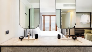 A modern hotel bathroom with a large sink, two mirrors, and a view of the sea through a large window. - Doryssa Lithos Hotel (Samos)
