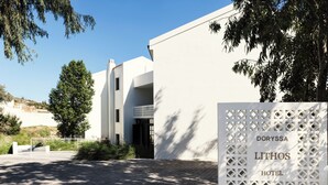 A modern hotel entrance with a white facade, a sign reading "DORYSSA LITHOS HOTEL," and a paved driveway.