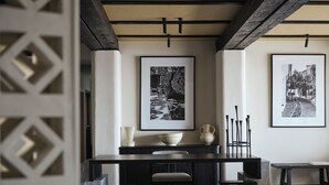 A modern dining area with a dark wooden table, two chairs, and a vase on the table. - Doryssa Lithos Hotel (Samos)
