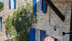 A stone building with blue shutters, a hanging lantern, and a tiled patio area. - A charming mas in Drôme provençale, a true family home (Puygiron)