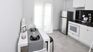 A modern kitchen with white cabinetry, a stainless steel refrigerator, a built-in oven, and a black countertop.