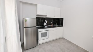 A modern kitchen with a stainless steel refrigerator, a built-in oven, and a black marble backsplash.