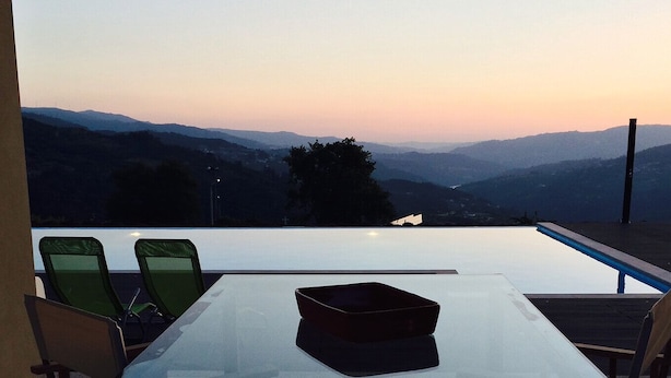 A dining area with a table and chairs overlooking a mountainous landscape at sunset. - Vald'arêgos Douro Turismo Rural (Resende)
