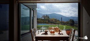 Uma sala de jantar com uma mesa posta para dois, com vista para uma piscina e montanhas.