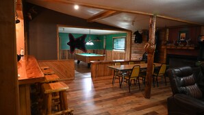 A wooden interior with a pool table, bar area, and seating. - Bushy Beaver Bar (Big Falls)