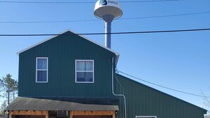 A two-story building with a green exterior, a water tower on top, and a sign that reads "FALLS." - Bushy Beaver Bar (Big Falls)