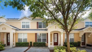 A row of townhouses with a central driveway, each with a front door and windows. - Charming 3BR Townhome - Private Pool - Walk to Clubhouse - 9 Min Disney! (Kissimmee)