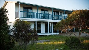 A two-story house with a balcony, a covered porch, and a front yard with rocks and bushes. - Casadelmar - Prime Position, With Sea Views (Marion Bay)