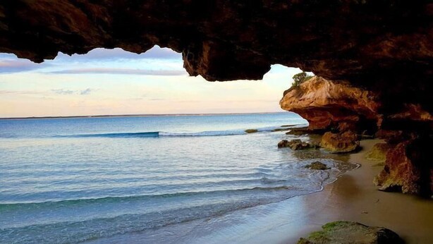 A beach scene with a cave entrance, calm sea, and rocky shoreline. - Casadelmar - Prime Position, With Sea Views (Marion Bay)