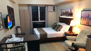 A hotel room with a bed, desk, chair, and a TV mounted on the wall. - 27th Flr Condo 2 w/WIFI @ IT Park Avida Riala Twrs (Cebu City)