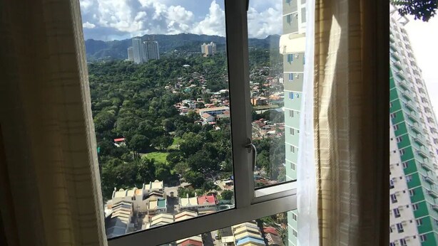A view from a window overlooking a cityscape with buildings and greenery. - 27th Flr Condo 2 w/WIFI @ IT Park Avida Riala Twrs (Cebu City)