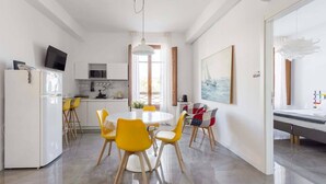 Une cuisine moderne avec des meubles blancs, un four à micro-ondes et un coin repas comprenant une table ronde et des chaises jaunes.