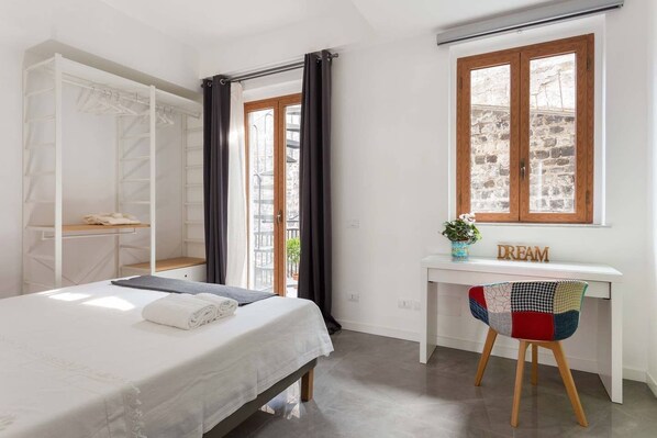 A bedroom with a bed, a desk, a chair, and a wardrobe.