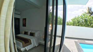 A bedroom with a bed, pillows, and a nightstand. There is a window with a view of a swimming pool and greenery outside. - Luxury Villa with privet outdoor swiming pool. (Kundasale)