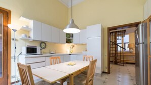 A compact kitchen with white cabinets, a dining table with four chairs, a microwave, and a refrigerator. - Duomo View Rooftop Terrace - Bright & Quiet 3 Bedroom 2 Bath (Firenze)