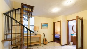 A staircase with wooden steps and black railings, a small table with a lamp, a guitar, and a painting on the wall. - Duomo View Rooftop Terrace - Bright & Quiet 3 Bedroom 2 Bath (Firenze)