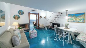 A spacious living area with a blue-tiled floor, a sofa, a dining table, and a staircase. - Casa Stella Marisa Positano - Unique Sea View Terrace near Beach & Center (Positano)