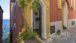 A narrow street with a building featuring a yellow and red facade, an arched doorway, and a small potted plant. - Casa Stella Marisa Positano - Unique Sea View Terrace near Beach & Center (Positano)