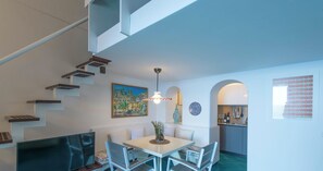A modern interior with a dining area, kitchen, and staircase.