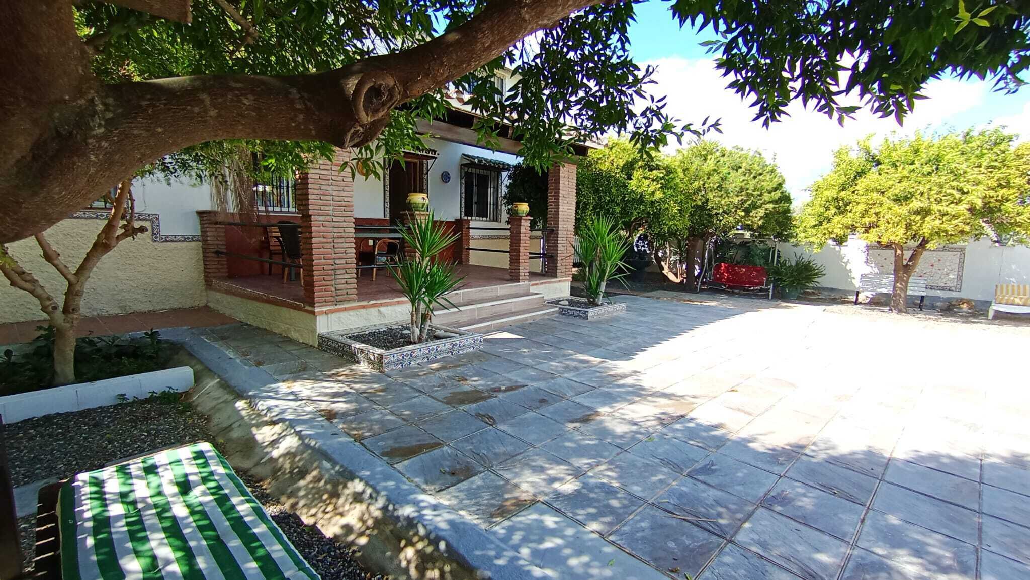 A patio area with a tiled floor, a small seating area, and a building with a brick facade.