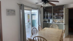 A dining area with a wooden table and chairs, a ceiling fan, and a kitchen area with open shelving. - Hideout On Lake Delton ( Known as the Getaway ) (Lake Delton)